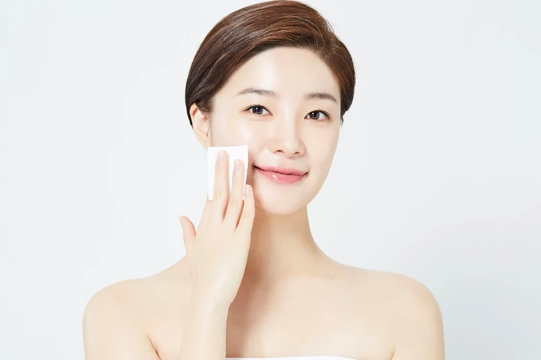 A client cleansing her skin with a cotton pad