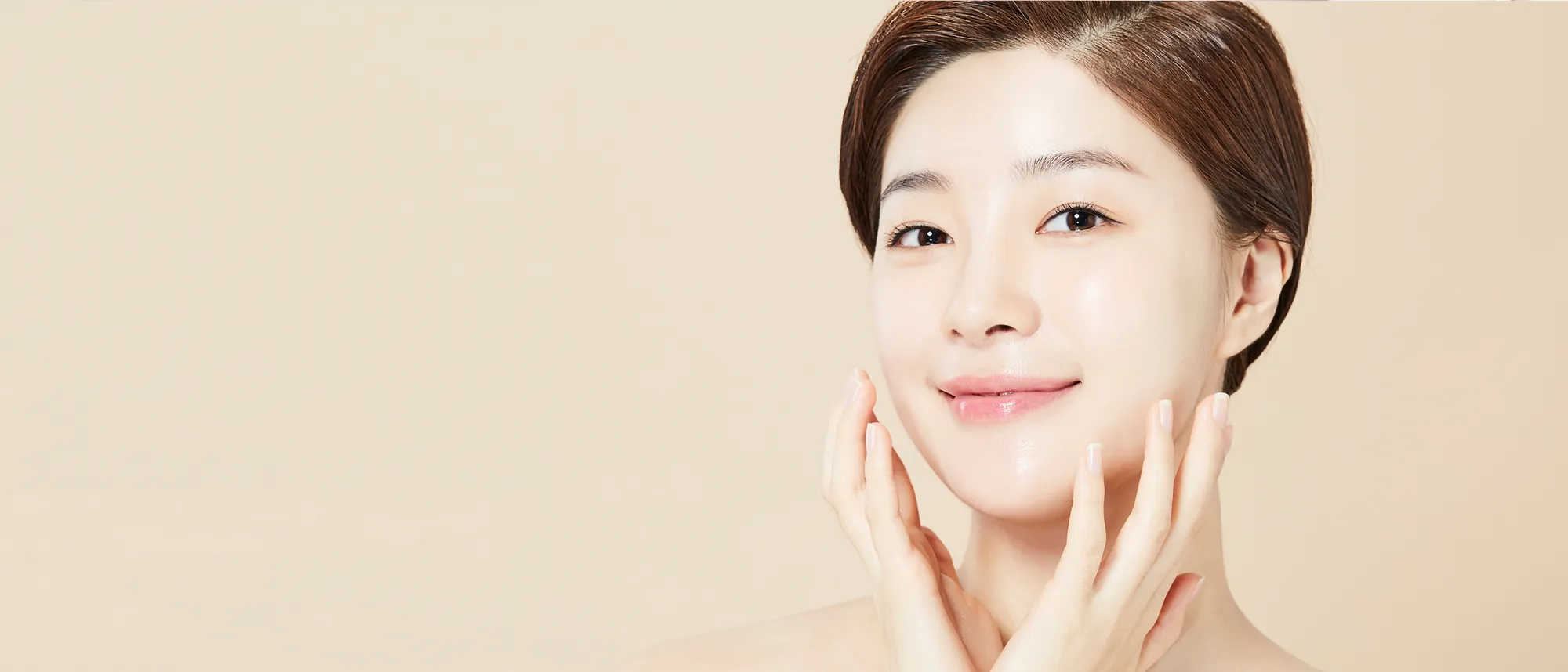 A client with radiant skin resting her hands on her cheeks