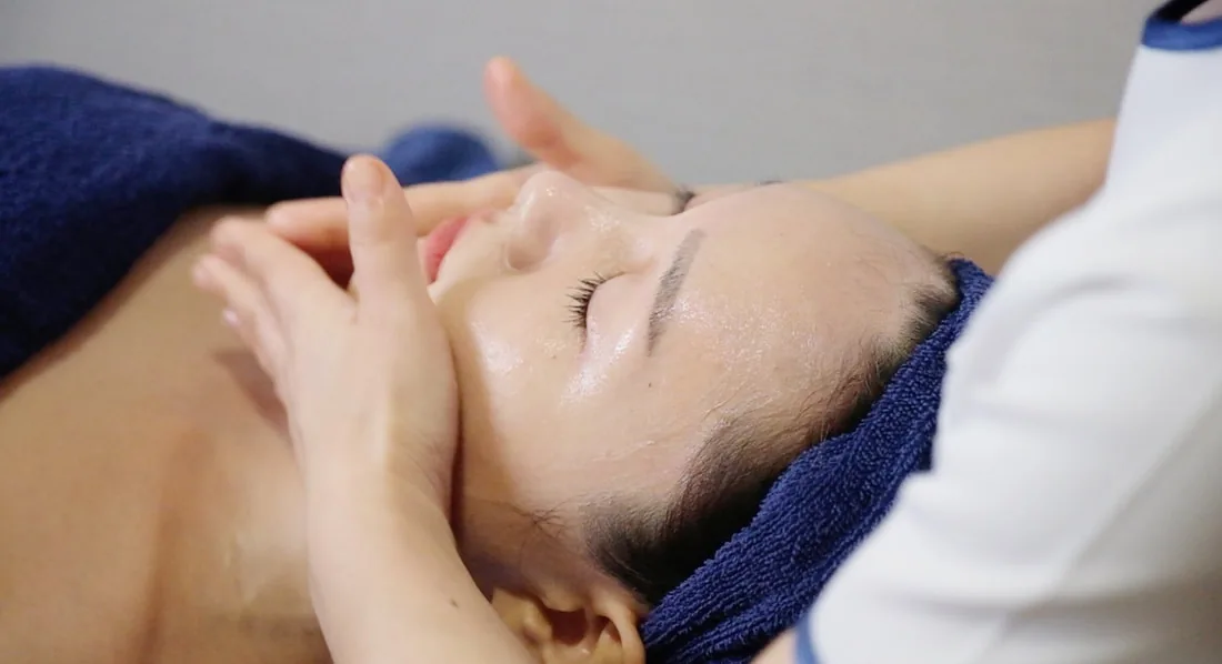 A therapist massaging a client’s face during a facial