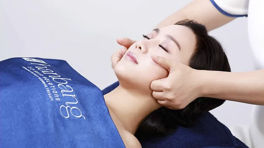 A Hanbang therapist pressing along a client's cheekbones during Geunmak therapy